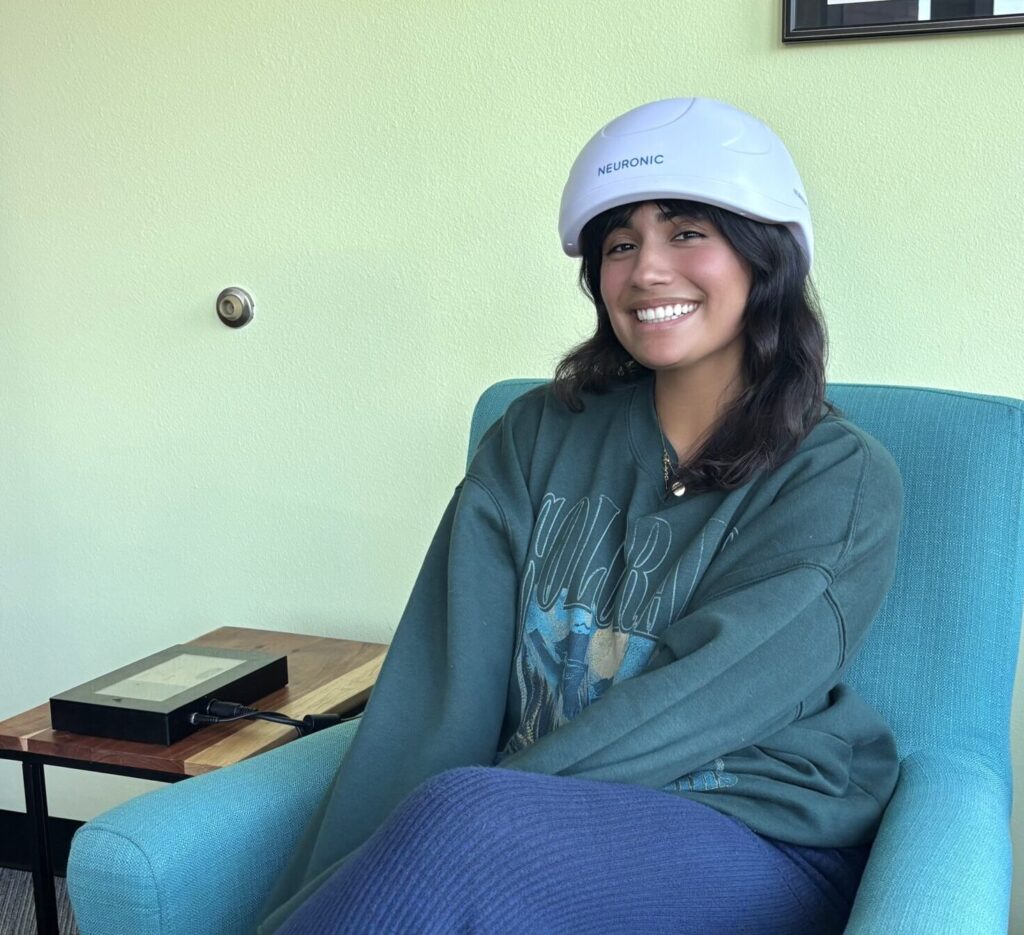 Client relaxing during a photobiomodulation (PBM) session wearing the Neuronic Neuradiant 1070 helmet at Healthy Within, San Diego