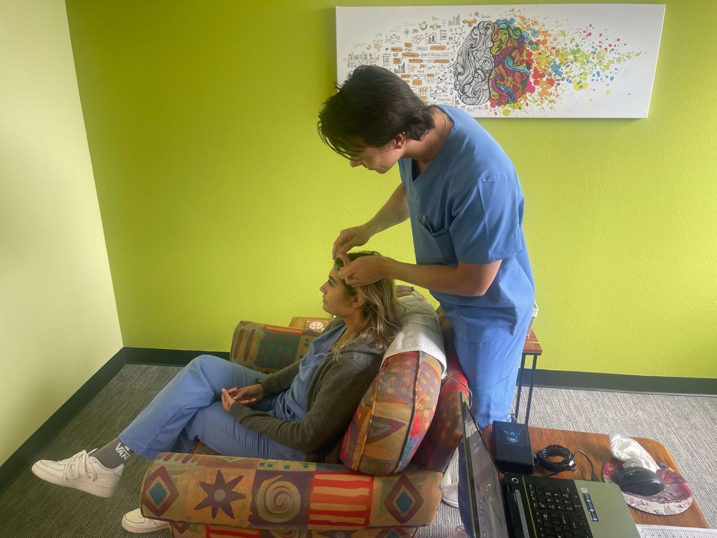 Client relaxing in a chair while a Healthy Within technician places Direct Neurofeedback sensors in San Diego